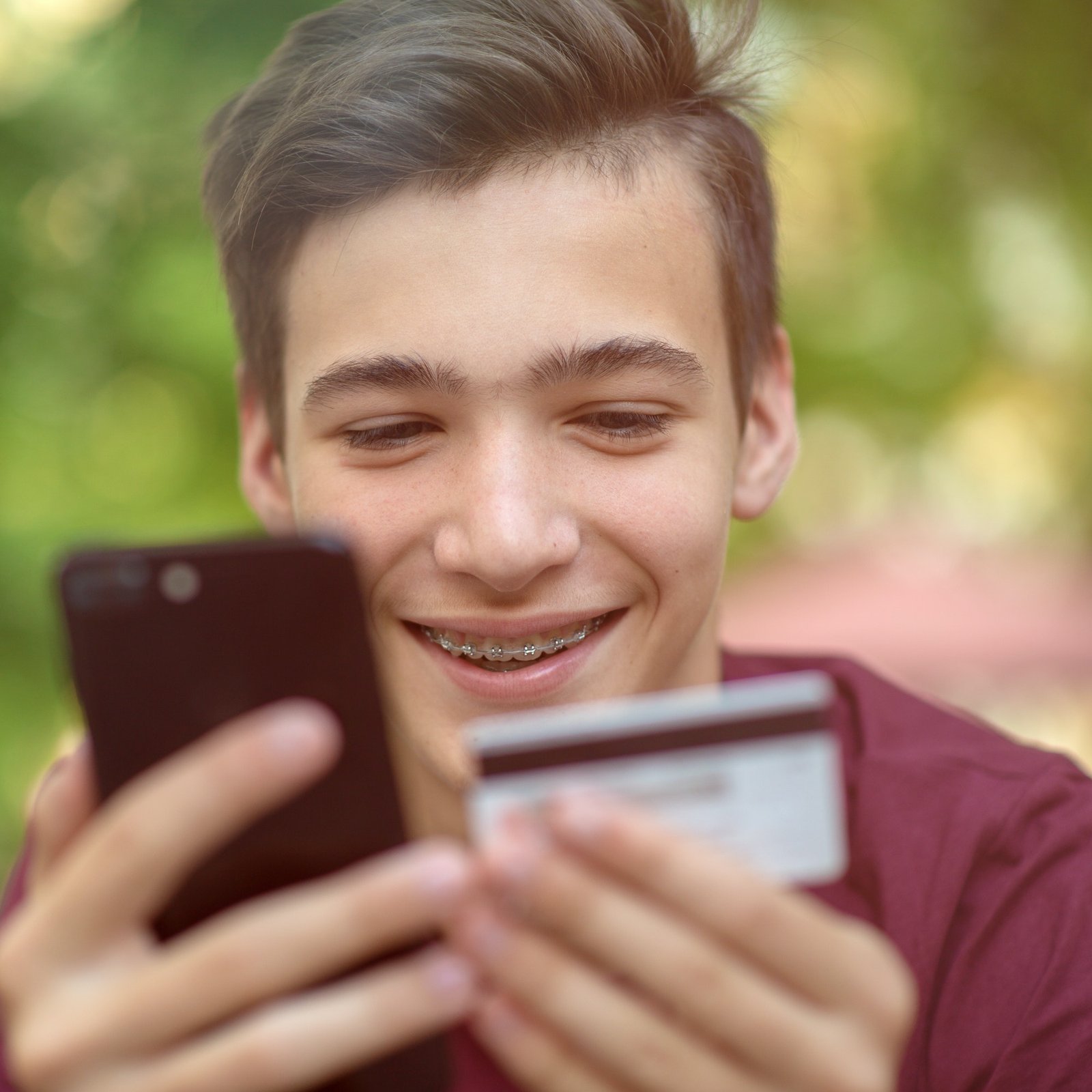 Happy young man is using smartphone and bank card for online shopping